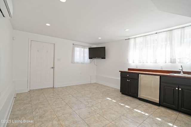 kitchen with baseboards, a sink, dark cabinetry, recessed lighting, and a wall unit AC