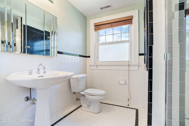 bathroom featuring visible vents, toilet, tile walls, wainscoting, and tile patterned floors