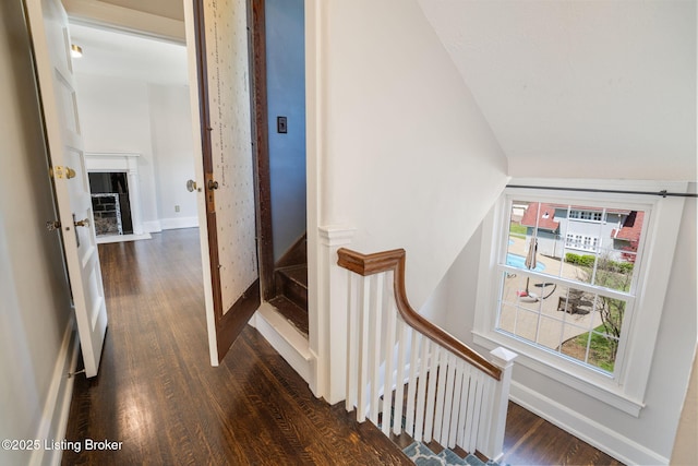 staircase featuring baseboards, plenty of natural light, vaulted ceiling, and wood finished floors