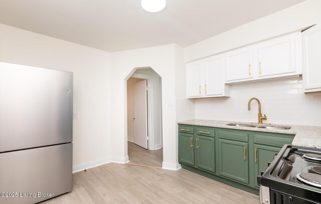 5512 Mae Ct, Louisville, KY 40214 - kitchen with arched walkways, freestanding refrigerator, a sink, black range with electric cooktop, and white cabinetry