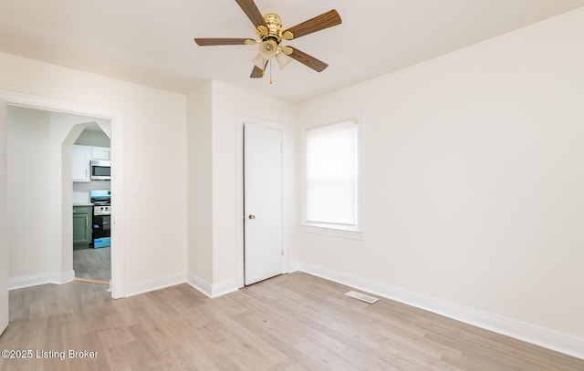 5512 Mae Ct, Louisville, KY 40214 - spare room featuring visible vents, baseboards, ceiling fan, light wood-type flooring, and arched walkways