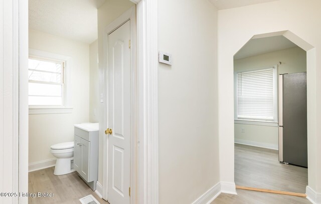 5512 Mae Ct, Louisville, KY 40214 - corridor featuring visible vents, light wood-style floors, arched walkways, and baseboards