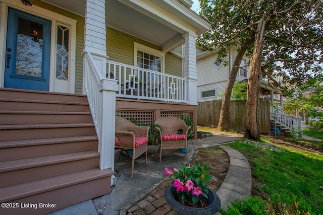 exterior space featuring covered porch, fence, and stairs