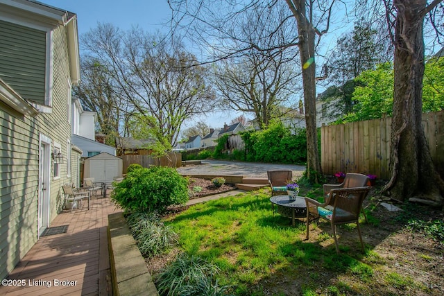 view of yard featuring an outbuilding, a shed, a fenced backyard, and a deck