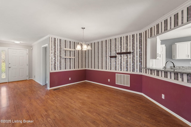 1501 Eagle Nest Way, Lyndon, KY 40222 - unfurnished dining area featuring a chandelier, crown molding, wood finished floors, baseboards, and wallpapered walls