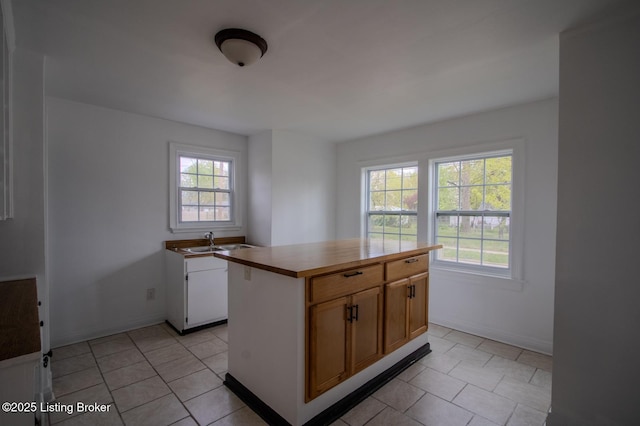 1301 Central Ave, Louisville, KY 40215 - kitchen with a sink, light tile patterned floors, a center island, and baseboards