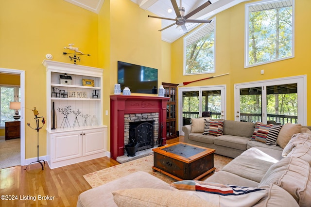 living room with a ceiling fan, wood finished floors, a high ceiling, a fireplace, and baseboards