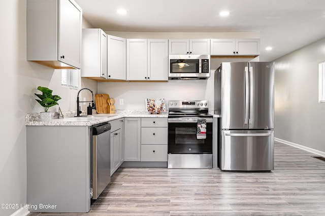 kitchen with recessed lighting, appliances with stainless steel finishes, light wood-style floors, and a sink
