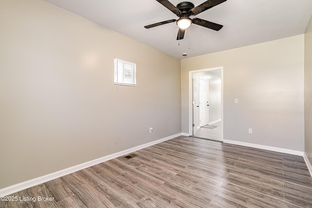 spare room featuring visible vents, baseboards, wood finished floors, and a ceiling fan