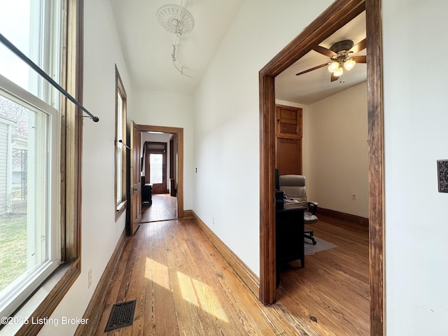 hall with light wood-style floors, an office area, and baseboards