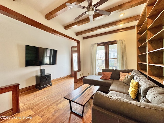 living area featuring a ceiling fan, beam ceiling, light wood finished floors, and baseboards