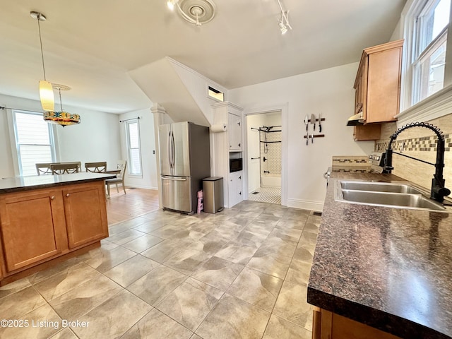 kitchen featuring freestanding refrigerator, a sink, dark countertops, and tasteful backsplash