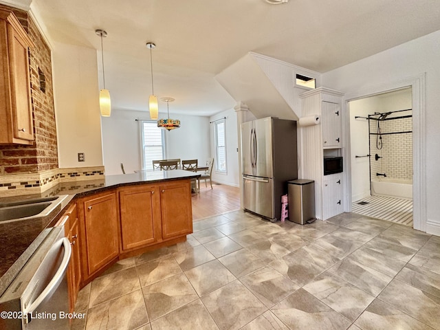 kitchen with stainless steel appliances, brown cabinets, decorative backsplash, decorative light fixtures, and a peninsula