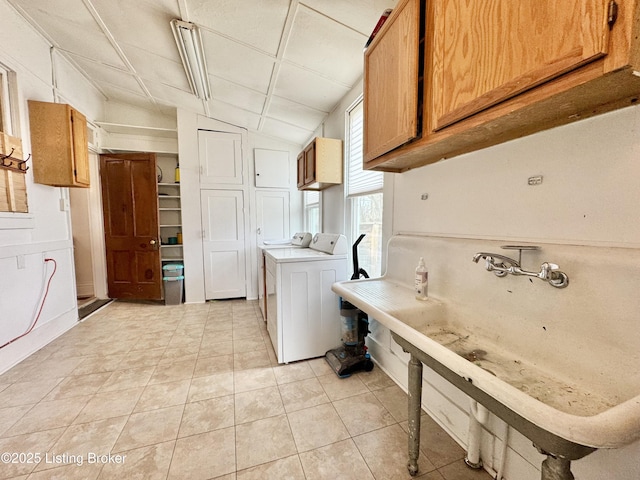 kitchen featuring washer / dryer, vaulted ceiling, light tile patterned flooring, light countertops, and brown cabinetry