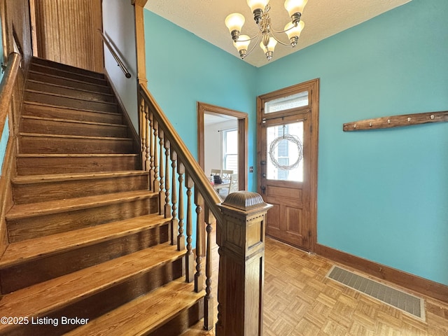 foyer with a chandelier, baseboards, and stairs