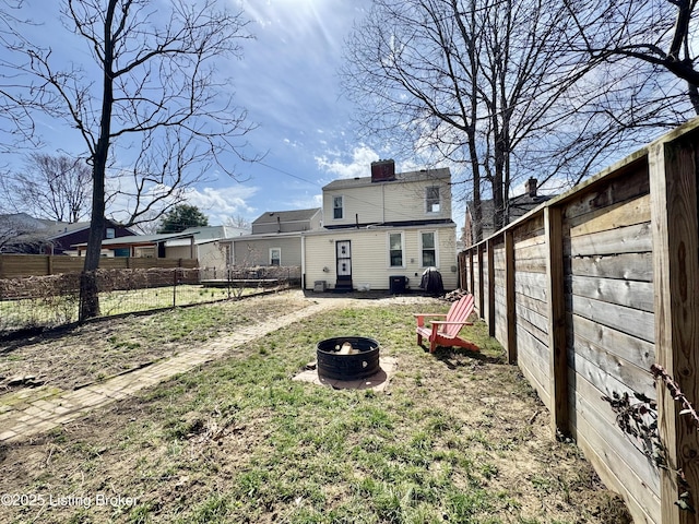 back of property with a fire pit, fence, a chimney, and central air condition unit