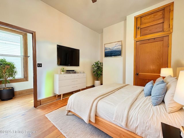 bedroom featuring light wood-style floors, baseboards, and vaulted ceiling