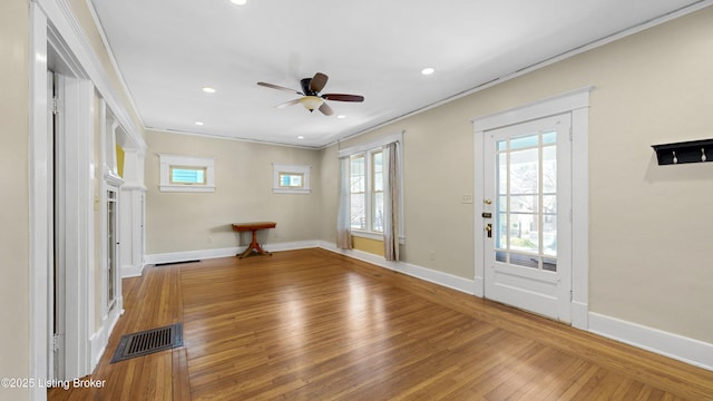 foyer featuring hardwood / wood-style floors, baseboards, visible vents, ornamental molding, and ceiling fan