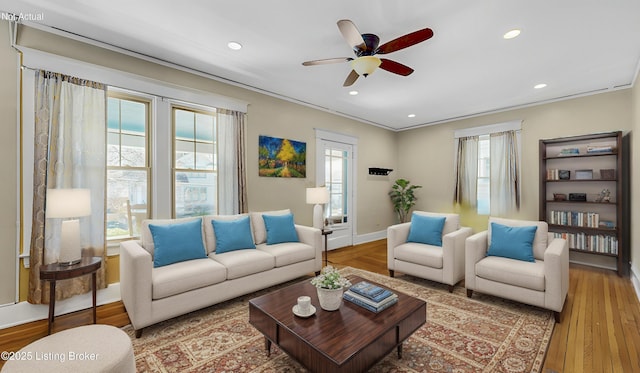 living area featuring a wealth of natural light, ornamental molding, ceiling fan, and wood finished floors