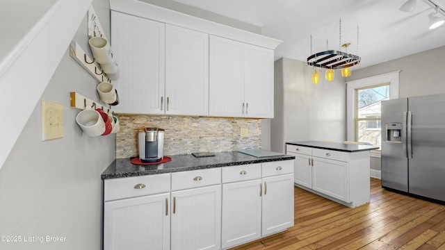kitchen featuring white cabinetry, light wood-style flooring, tasteful backsplash, and stainless steel refrigerator with ice dispenser