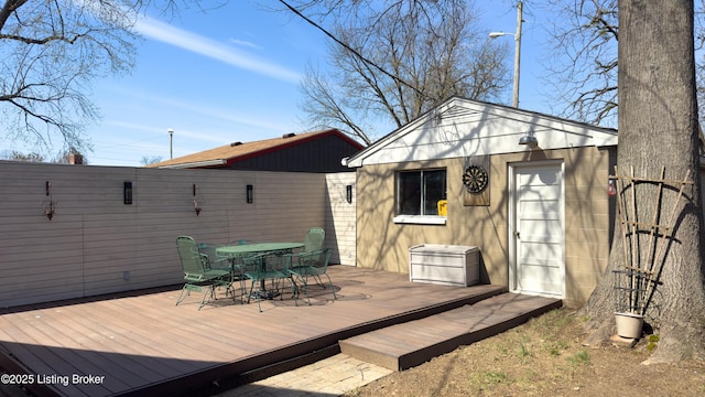 wooden deck with an outdoor structure, outdoor dining space, and fence