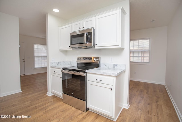3833 Jupiter Rd, Louisville, KY 40218 - kitchen with stainless steel appliances, light countertops, light wood finished floors, white cabinets, and healthy amount of natural light