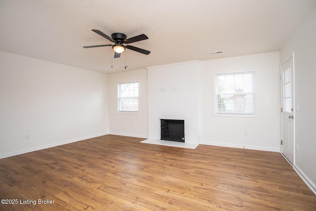 3833 Jupiter Rd, Louisville, KY 40218 - unfurnished living room with a ceiling fan, a brick fireplace, wood finished floors, baseboards, and a textured ceiling