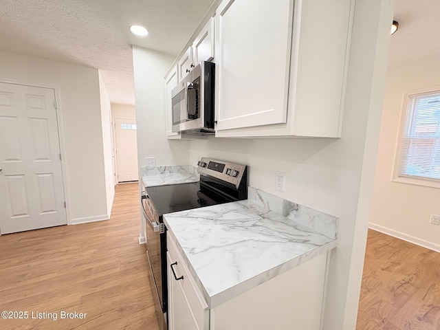 3833 Jupiter Rd, Louisville, KY 40218 - kitchen with stainless steel appliances, white cabinetry, light wood-style flooring, a textured ceiling, and baseboards