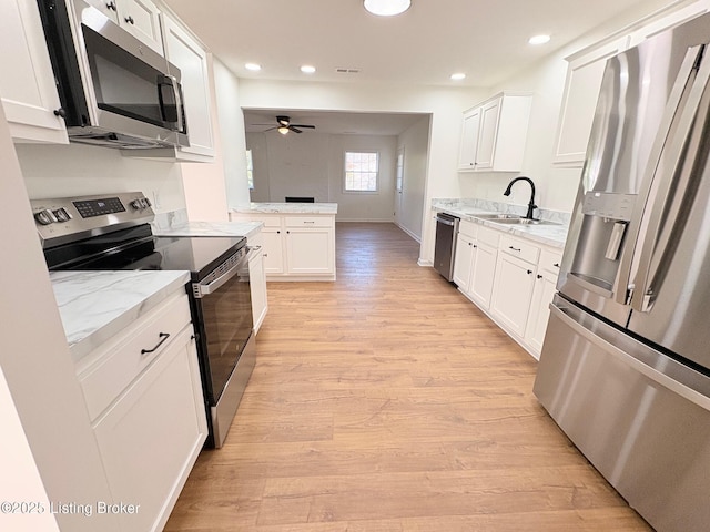 3833 Jupiter Rd, Louisville, KY 40218 - kitchen featuring stainless steel appliances, a sink, ceiling fan, light wood finished floors, and white cabinetry
