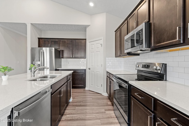 8806 Warbler Branch Way, Louisville, KY 40229 - kitchen with light stone counters, a sink, stainless steel appliances, dark brown cabinetry, and light wood-type flooring