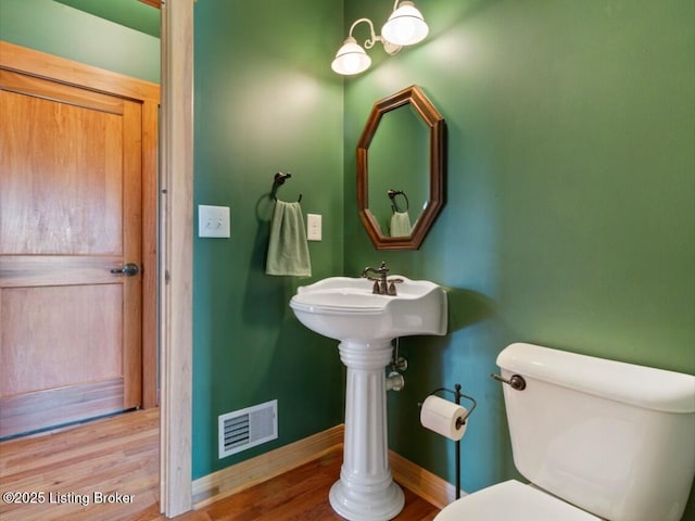 bathroom featuring baseboards, visible vents, wood finished floors, and toilet