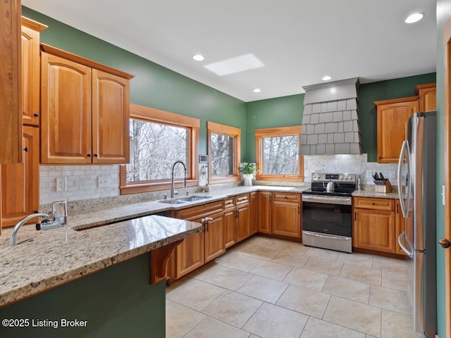 kitchen with premium range hood, backsplash, a sink, light stone counters, and appliances with stainless steel finishes