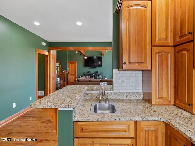 kitchen featuring recessed lighting, baseboards, backsplash, a sink, and wood finished floors