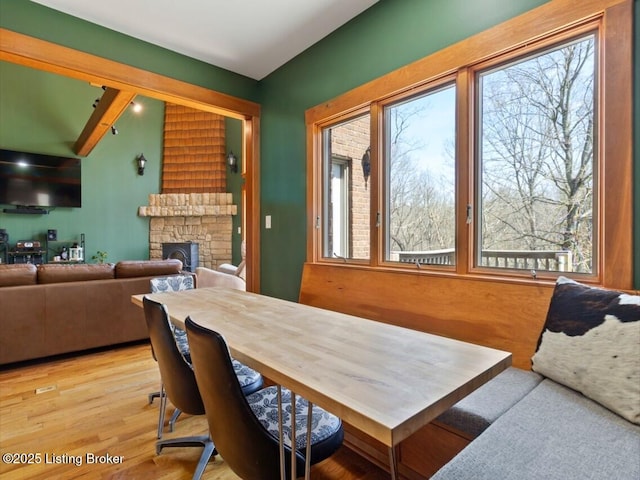 dining area featuring a fireplace, light wood-type flooring, and plenty of natural light