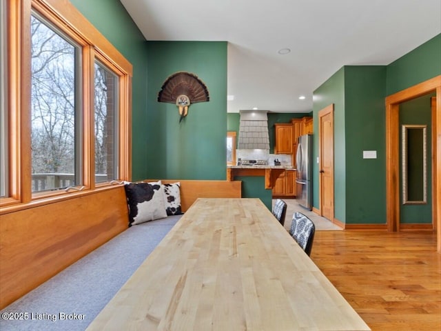 dining area with baseboards, light wood finished floors, and recessed lighting