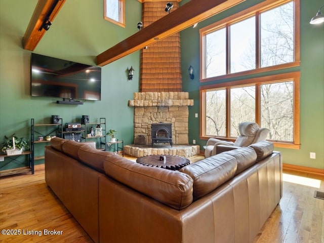 living area with baseboards, beamed ceiling, a high ceiling, and light wood-style flooring