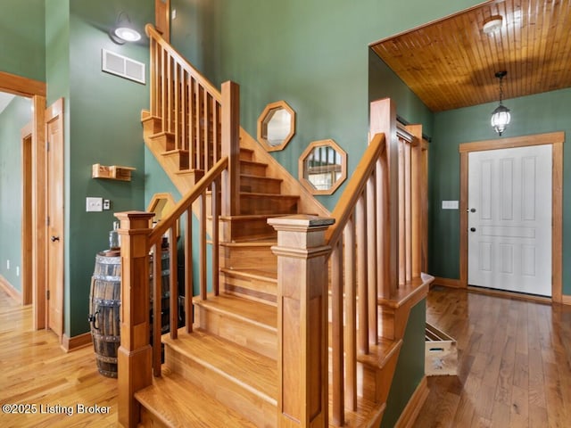 entrance foyer featuring baseboards, visible vents, wood finished floors, and stairway