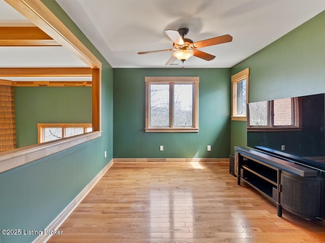 living room featuring baseboards, ceiling fan, and wood finished floors