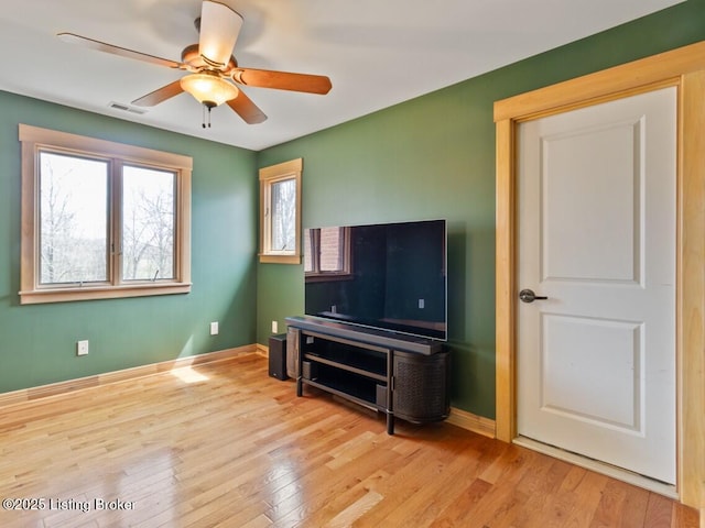 interior space with baseboards, visible vents, hardwood / wood-style flooring, and a ceiling fan