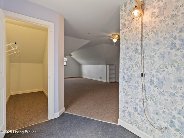 bonus room featuring a ceiling fan, baseboards, dark colored carpet, and vaulted ceiling