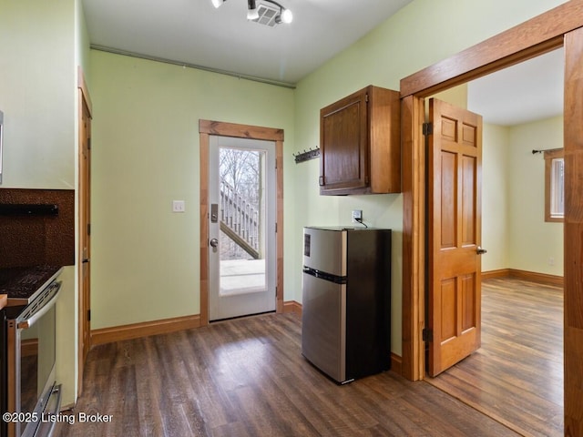 kitchen featuring dark wood-style flooring, stainless steel appliances, and baseboards