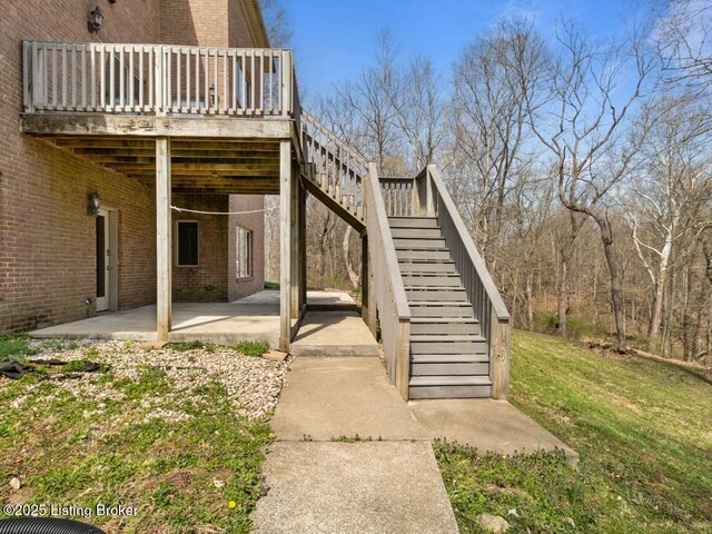 view of home's exterior featuring a patio area, stairway, a deck, brick siding, and a yard