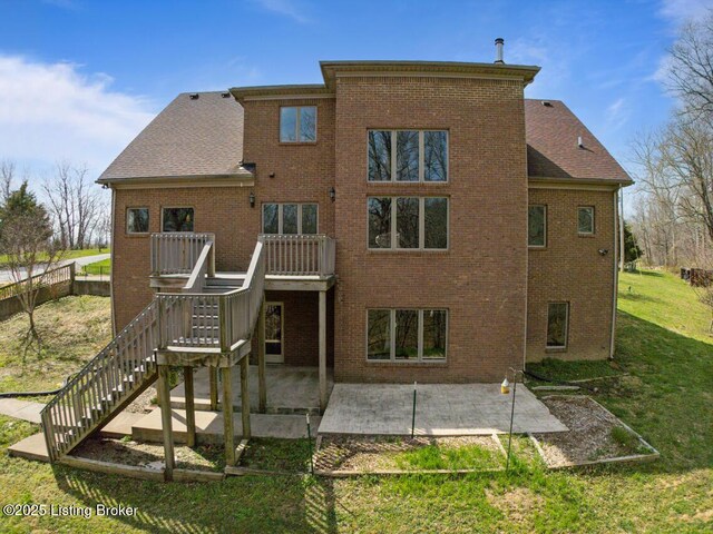 rear view of house with a lawn, brick siding, stairway, and a patio area