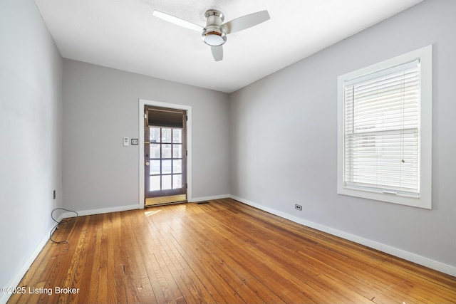 unfurnished room featuring hardwood / wood-style flooring, a ceiling fan, and baseboards