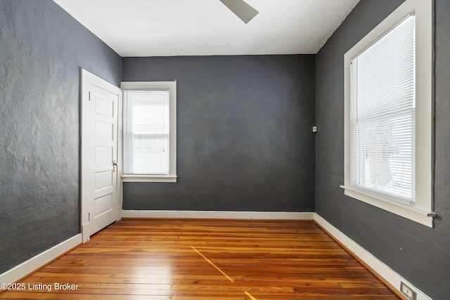unfurnished room with baseboards and wood-type flooring