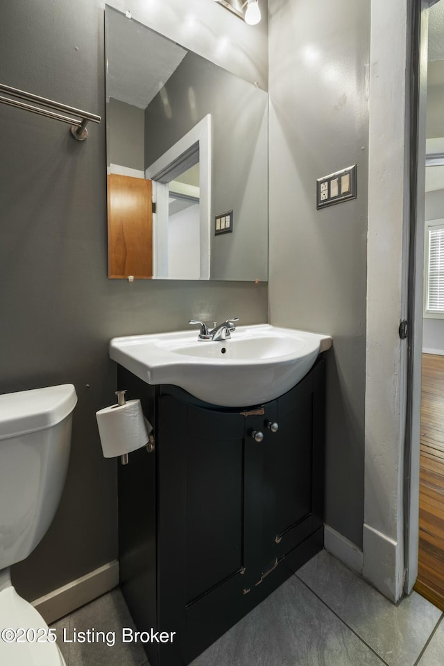 bathroom featuring baseboards, toilet, and vanity