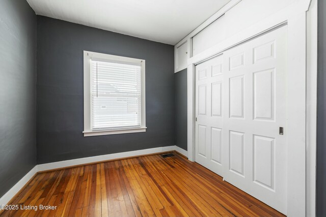 unfurnished bedroom with dark wood-type flooring, baseboards, and a closet