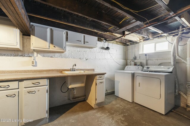 clothes washing area featuring a sink, cabinet space, and washer and clothes dryer