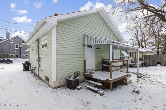 snow covered rear of property featuring a wooden deck and fence