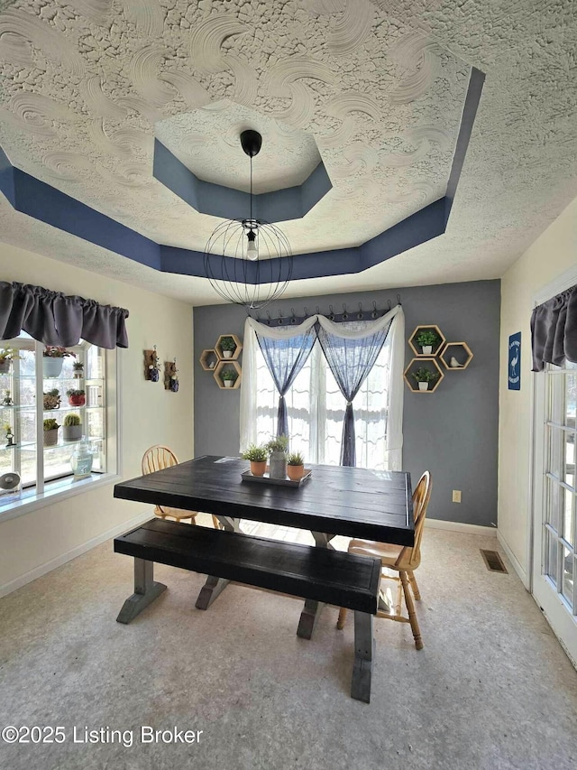 dining area with visible vents, baseboards, light carpet, a textured ceiling, and a raised ceiling